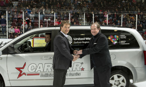 Collin Welsh of CARSTAR hands over the keys to a refurbished van to Robert Howard of the United Way of Durham at an Oshawa Generals game. The van was refurbished thanks to Durham Region CARSTAR stores, Enterprise Rent-A-Car and Discount Car and Truck Rentals.