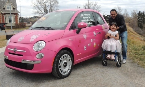Rachid El Madawi, Julia Khaled, and the Fiat 500 El Madawi's shop refurbished for auction. Proceeds from the auction will help to pay for an operation Khaled needs due to her cerebral palsy.
