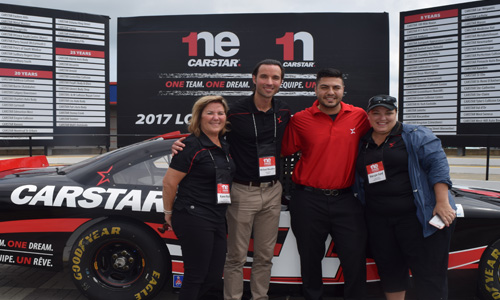 Some of CARSTAR's corporate staff, standing before the long list of shops celebrating their fifth, tenth, twentieth or twenty-fifth year as a CARSTAR facility. From left: Karen Rush, Michael Macaluso, and Margie Ford.
