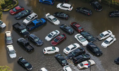 Cars are pushed together during heavy flooding in the center of a hotel compound, in Houston, Texas. Some of the aftereffects of Hurricane Harvey will likely include an increase in new car sales, and a rash of "title washing" as owners of uninsured vehicles try to recoup their losses.